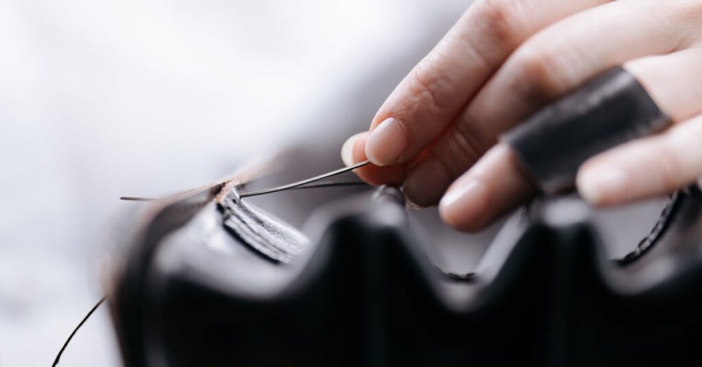 Close-up of a hand stitching leather, showcasing intricate craftsmanship and precision.